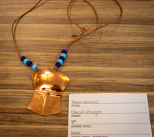A copper artwork and beaded necklace created by an Atnané Academy student