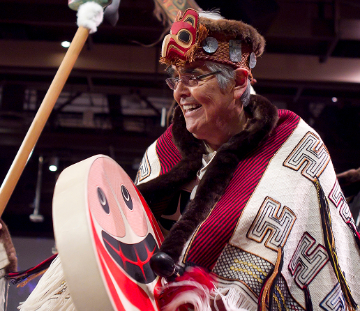 Haida master artist Robert Davidson wearing regalia and holding a carved dance paddle