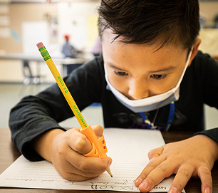 A student writing with a pencil during a classroom activity