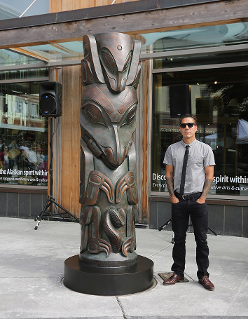Haida artist TJ Young beside his bronze Wasgo house post