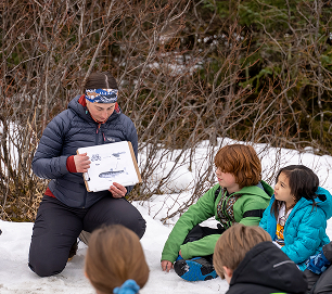 An educator reading to students outdoors in winter